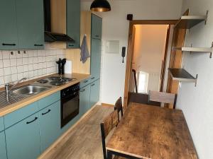 a kitchen with a wooden table and a kitchen with blue cabinets at Stefans Apartments C - 20 min bis DD Messe und Flughafen inkl Parkplatz in Willich