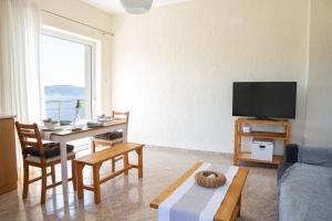 a living room with a table and a tv at Oasis Resort Pure Relaxation Serenity in Agia Marina Mikrolimanou