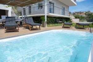 a large swimming pool with chairs and a house at Oasis Resort Pure Relaxation Serenity in Agia Marina Mikrolimanou