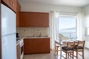 a kitchen with wooden cabinets and a table and a window at Oasis Resort Pure Relaxation Serenity in Agia Marina Mikrolimanou