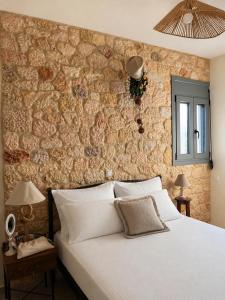 ein Schlafzimmer mit einem weißen Bett und einer Steinwand in der Unterkunft Ckamares in Sikéa