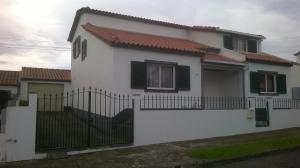 une maison blanche avec une clôture noire dans l'établissement Pedro Sousa Rooms na Relva, à Ponta Delgada