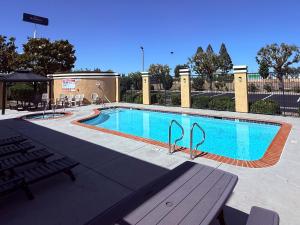 a large swimming pool with a picnic table and chairs at Baymont by Wyndham Manteca in Manteca