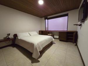 a bedroom with a large bed and a window at Apartamentos Percales in Bogotá