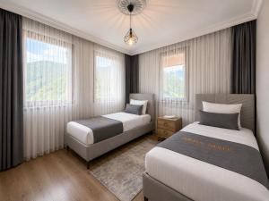 two beds in a room with two windows at İmera Suite Otel in Uzungöl +42 photos