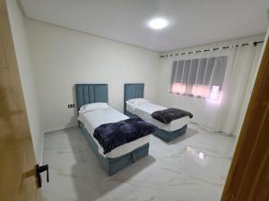 two beds in a room with white walls at Le calme d'ajdir in Ajdir