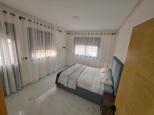 a bedroom with a bed and two windows at Le calme d'ajdir in Ajdir