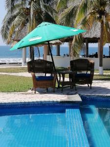 a table and chairs with an umbrella next to a pool at Hotel & Resort Casa Bella in El Hawaii