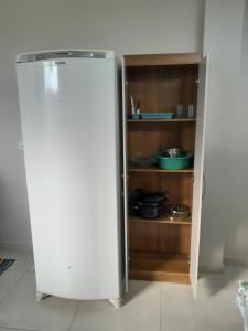 a white refrigerator in a kitchen with a shelf at Kitnet Perequê in Matinhos