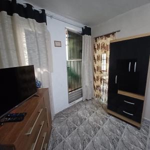 a living room with a flat screen tv next to a window at Casa Singela in Miguel Pereira