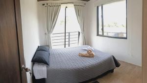 a teddy bear sitting on a bed in a bedroom at El Eden in Sáchica