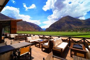 a patio with tables and chairs and mountains in the background at RUSTICA HOTELES CUSCO Urubamba in Urubamba