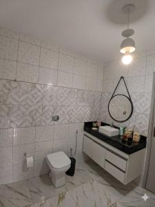 a bathroom with a toilet and a sink and a mirror at Estúdio moderno com cozinha america in Ilhéus