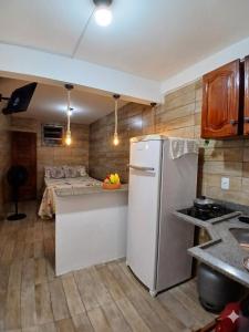 a kitchen with a white refrigerator and a table at Estúdio moderno com cozinha america in Ilhéus