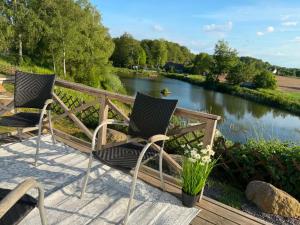 two chairs sitting on a deck next to a river at Möllergårdens Stugor in Ängelholm