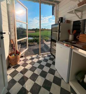 a kitchen with a checkered floor and a large window at Möllergårdens Stugor in Ängelholm