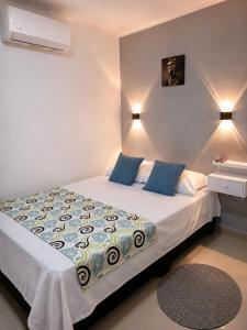 a bedroom with a bed with blue pillows at Hostal Caiman Del Rio in Barranquilla +13 photos