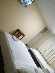 a bedroom with a bed with white sheets and a window at Hospedaje San Valentin in Capitan Concha