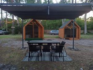 a picnic table and chairs under a tent with a house at Happy House Hel in Hel
