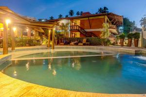 a swimming pool in front of a house at Pousada Praia Bela in Ilhéus