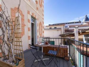 a balcony with a wooden table and chairs on a building at Parenthèse en Ville in Arcachon