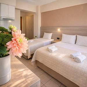 a hotel room with two beds and a vase with flowers at John & Eve Hotel in Paralia Katerinis