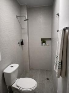 a white bathroom with a toilet and a shower at Hostal Caiman Del Rio in Barranquilla