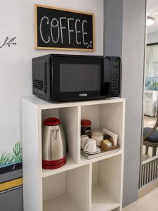 a microwave sitting on top of a white shelf at Hostal Caiman Del Rio in Barranquilla