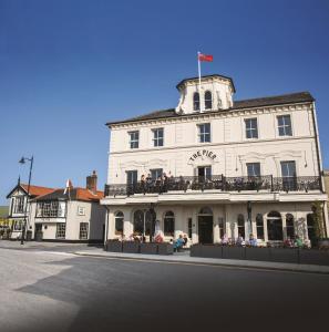 a white building with people sitting on a balcony at The Pier Hotel in Harwich