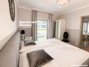 a bedroom with a large white bed with black pillows at Apartament Glamour - 5 Mórz - Basen - SPA - Sauna in Sianozety +25 photos