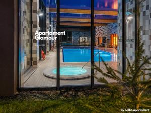 a reflection of a swimming pool in the window of a building at Apartament Glamour - 5 Mórz - Basen - SPA - Sauna in Sianozety
