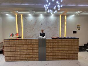 a man is standing behind a counter in a lobby at Tinchlik Plaza in Urganch