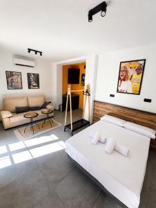 a bedroom with a white bed and a couch at Penthouse San Isidro 3 suites Terraza Privada Parking in Granada