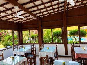 a dining room with tables and chairs and windows at Pousada Cantinho do Mar - pé na areia in Guarujá