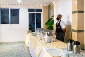 a man in apron standing next to a table with pots at Delfin Hotel Collection Rodadero in Rodadero