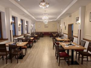 a restaurant with wooden tables and chairs and a chandelier at Konak Studenica 1186 in Kraljevo