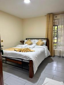 a bedroom with a large bed with white sheets at Entebbe Gardens Resort in Kitengela 