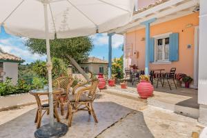 a table and chairs with an umbrella on a patio at Aiolos Rooms in Tsoukalades