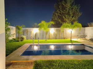 a swimming pool in the middle of a yard at night at Riad Elbahi in Marrakesh