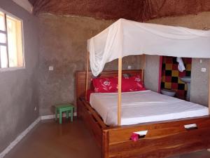 a bedroom with a wooden bed with a canopy at La Cabane Rasta - Mar Lodj in Mar Lodj