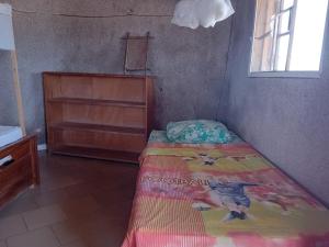 a small bedroom with a bed and a wooden dresser at La Cabane Rasta - Mar Lodj in Mar Lodj
