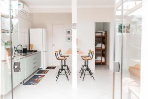 a white kitchen with a table and stools at The Beach House Estadias in Itapoa