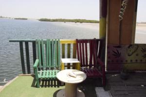two chairs and a table on a dock with the water at La Cabane Rasta - Mar Lodj in Mar Lodj