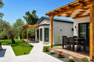 a patio with a table and chairs under a wooden pergola at Aivazidis Residence II in Skala Kallirachis