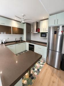 a kitchen with white cabinets and a stainless steel refrigerator at Penthouse San Isidro 3 suites Terraza Privada Parking in Granada