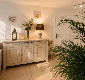a room with a white cabinet with a lamp and a plant at Le Aix Rotonde Mirabeau - Centre Ville Terrasse Garage in Aix-en-Provence