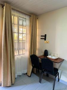 a table and chairs in a room with a window at Entebbe Gardens Resort in Kitengela  +18 photos