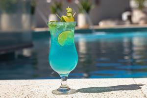 a blue drink sitting on a table next to a pool at Pousada Praia Bela in Ilhéus +58 photos