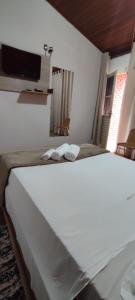 a bedroom with a bed with two slippers on it at Hospedagem Vista Real in Casa Branca