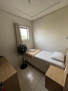 a room with two beds and a window and a fan at Hotel Piracema in Caruaru